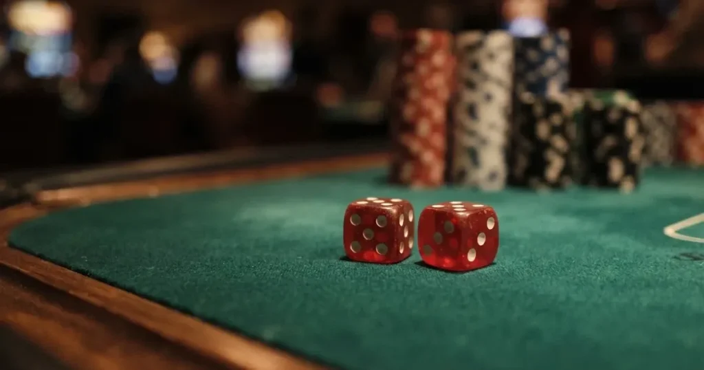 Röda tärningar vilar på grönt filt, bakom dem suddiga torn av spelmarker i kvällsdunklet — casinospel i sverige
